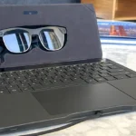 Gafas inteligentes Zero UI en estuche con teclado portátil sobre mesa de mármol – tecnología sin pantallas